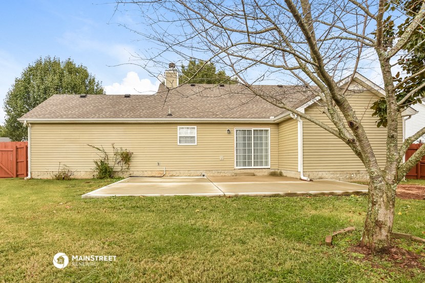 the back of a yellow house with a patio in the yard