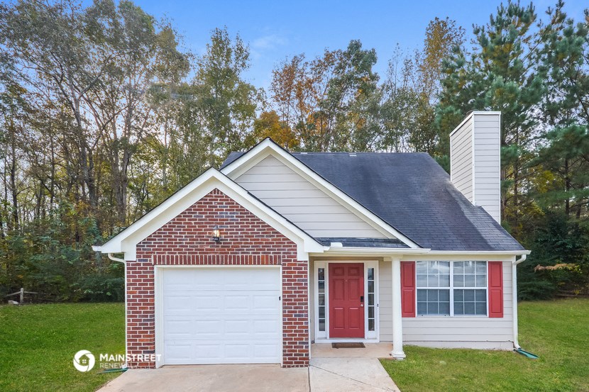 a small brick house with a red door and a white garage