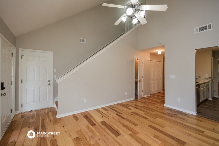 a living room with wood flooring and a ceiling fan