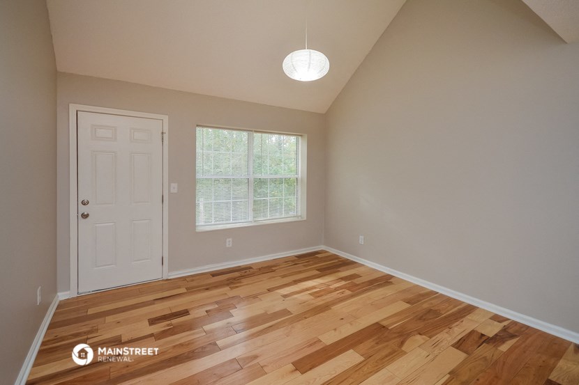 the spacious dining room with hardwood flooring and a white door