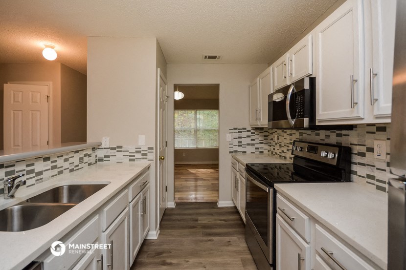 an empty kitchen with white cabinets and black appliances