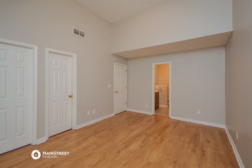 an empty living room with a wooden floor and white doors