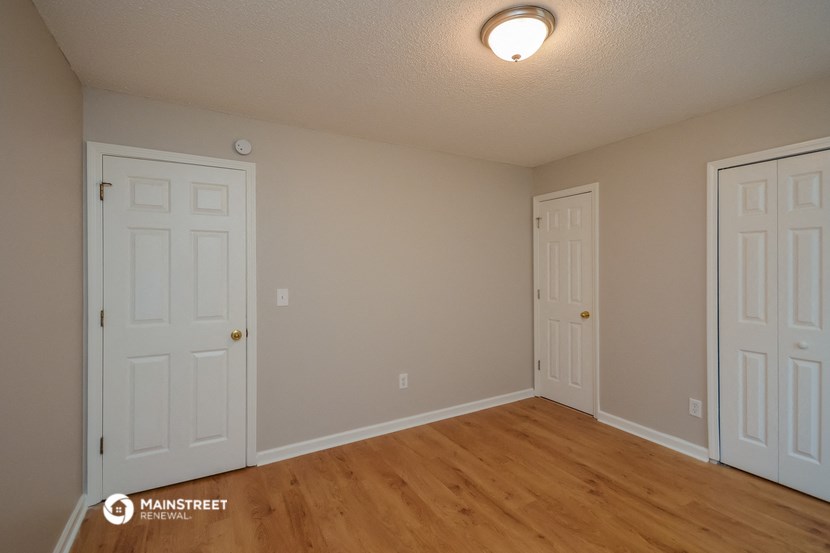 the living room of a house with two doors and a wood floor