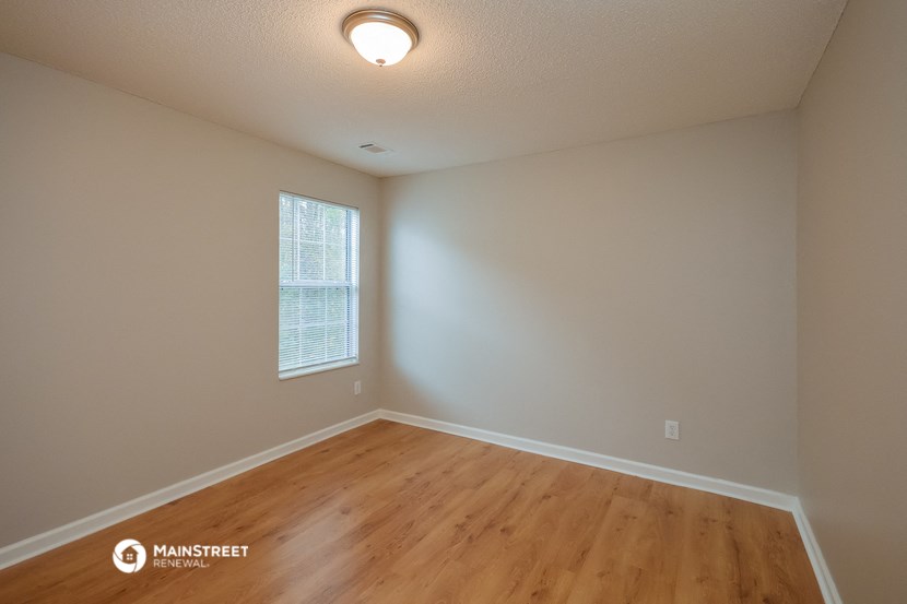 an empty living room with wood floors and a window