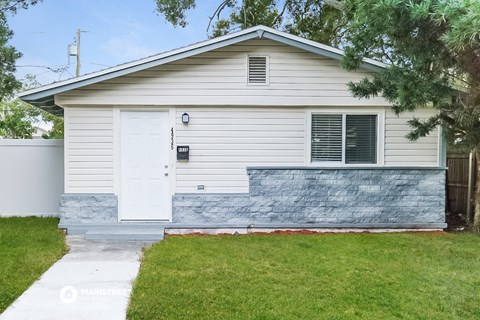 a white house with a stone wall on the side of it