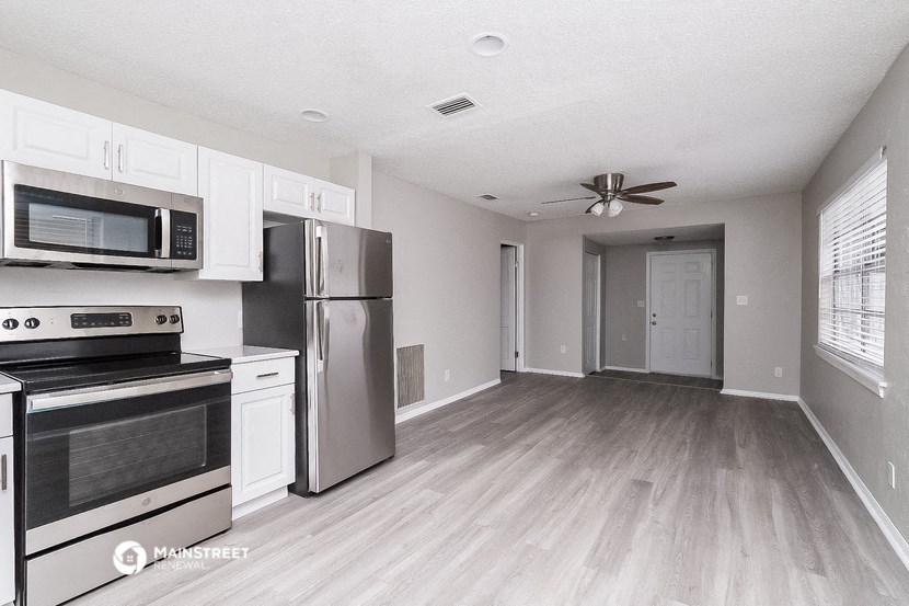 an empty kitchen with stainless steel appliances and white cabinets