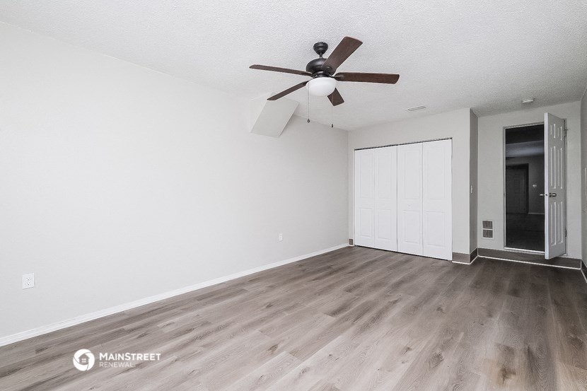 an empty living room with white walls and a ceiling fan