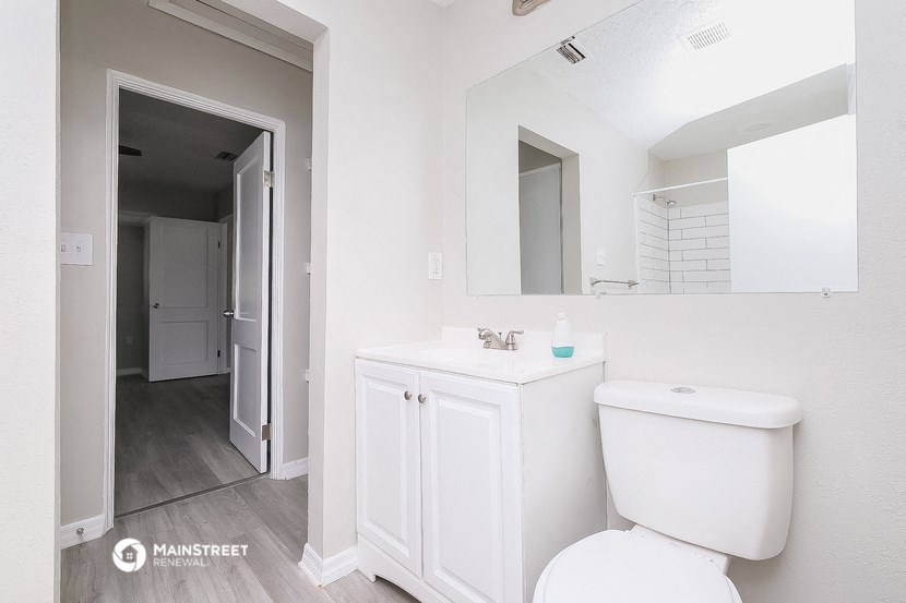 a white bathroom with a white toilet and a large mirror