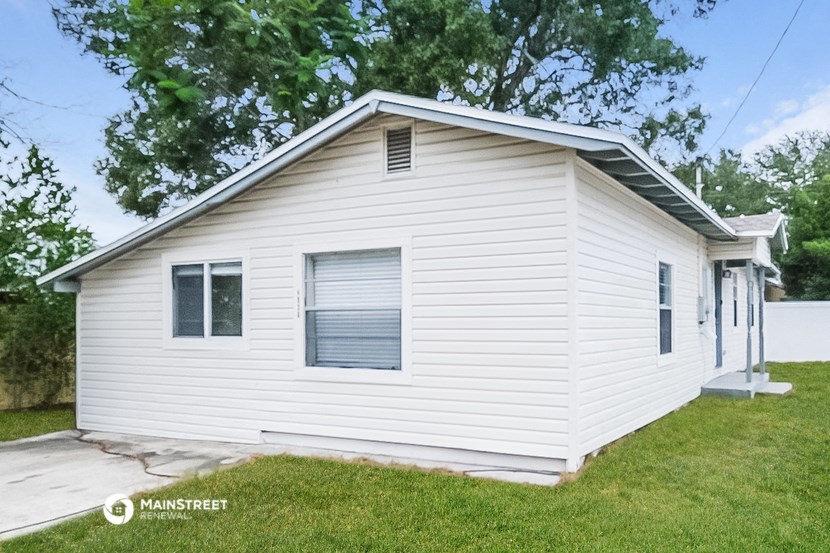a small white house with white siding on the side of a yard