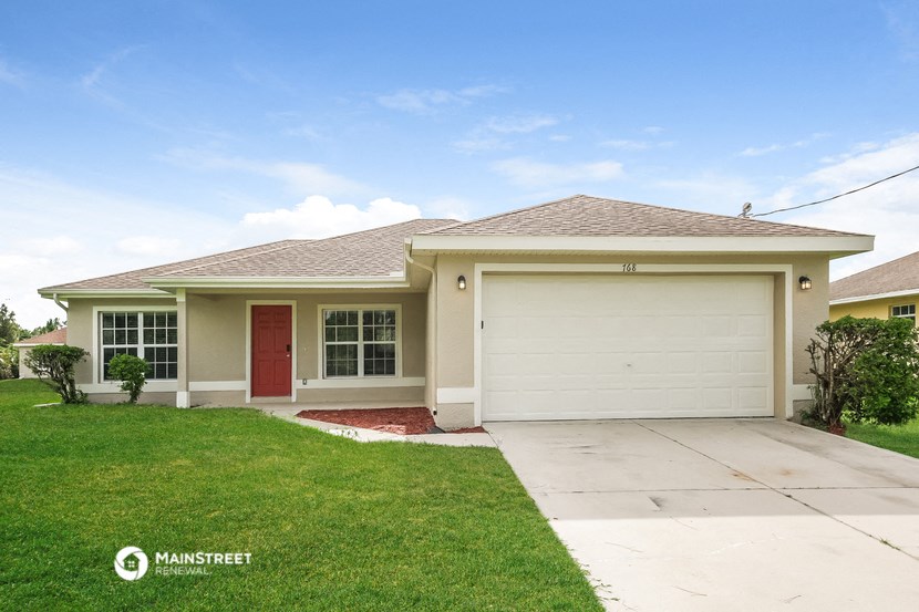 a beige house with a garage door and a lawn