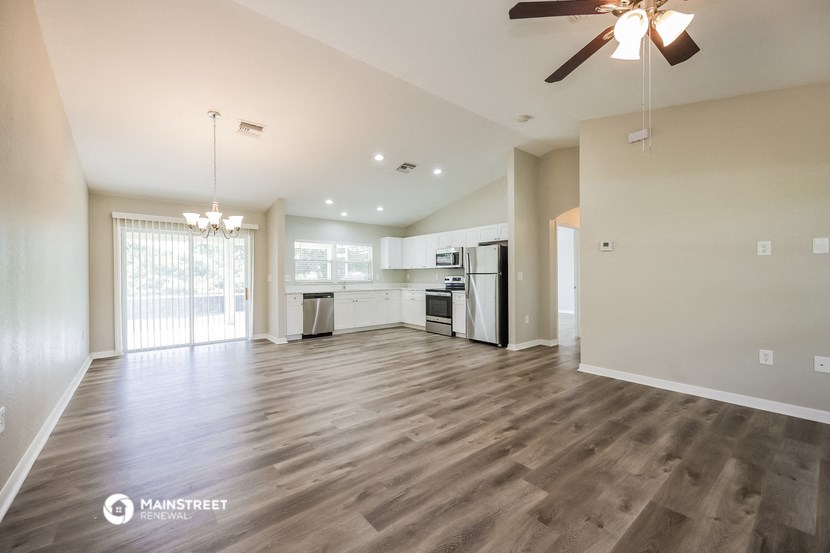 an empty living room and kitchen with a ceiling fan