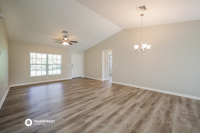 an empty living room with wood flooring and a ceiling fan