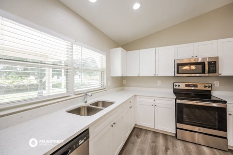 a kitchen with white cabinets and a sink and a window