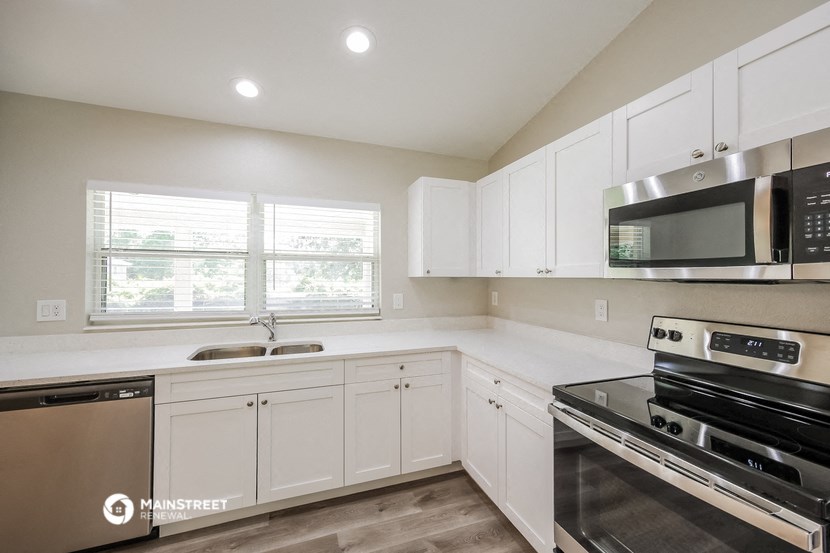 a white kitchen with stainless steel appliances and white cabinets