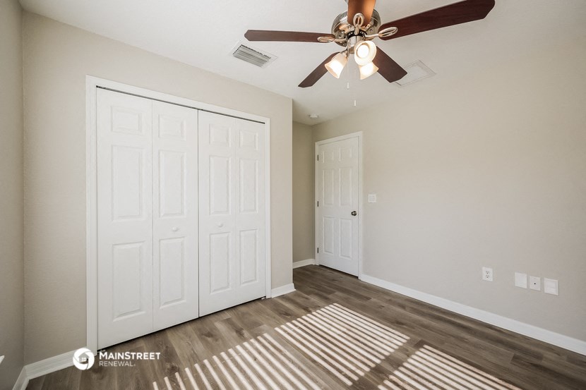 a bedroom with a ceiling fan and a closet
