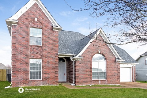 the front of a brick house with an arched window and a white door