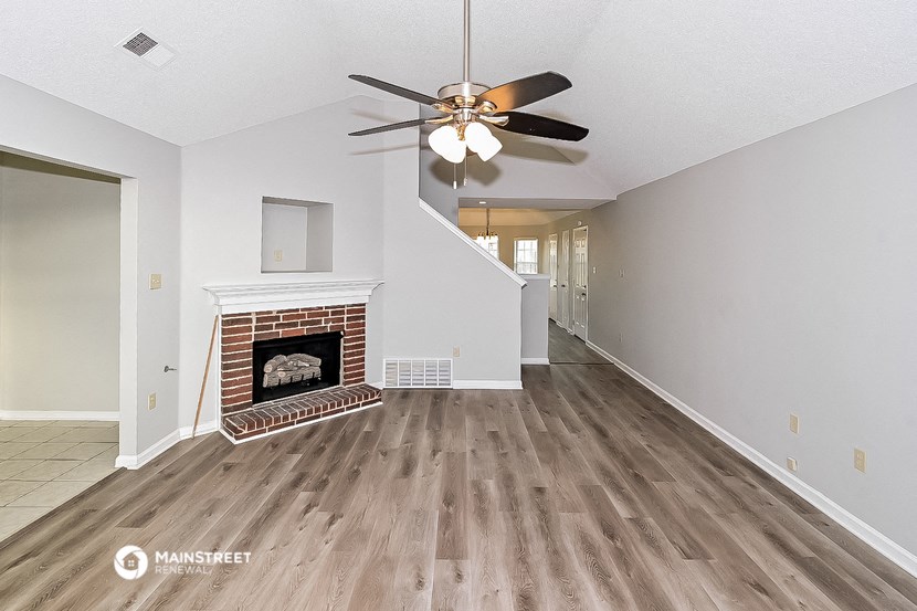 a living room with a fireplace and a ceiling fan