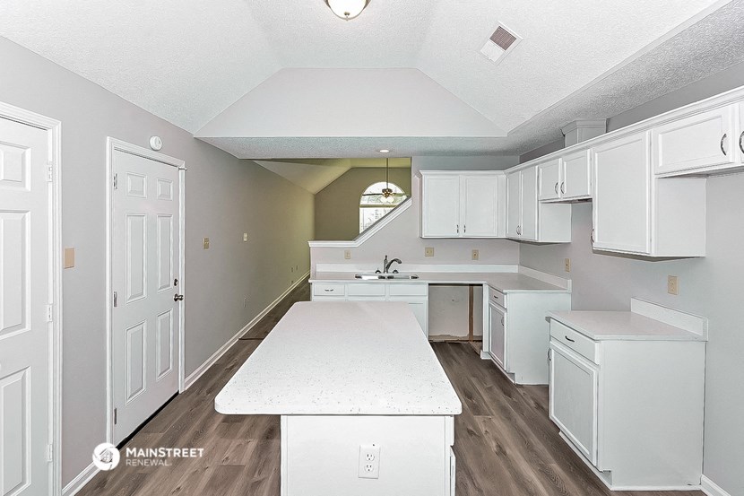 an open kitchen with white cabinets and a white counter top