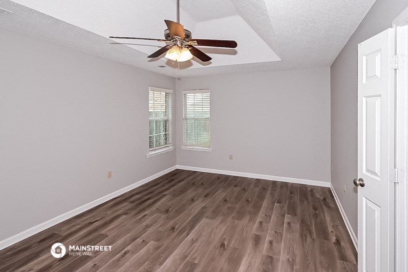 the spacious living room with hardwood floors and a ceiling fan