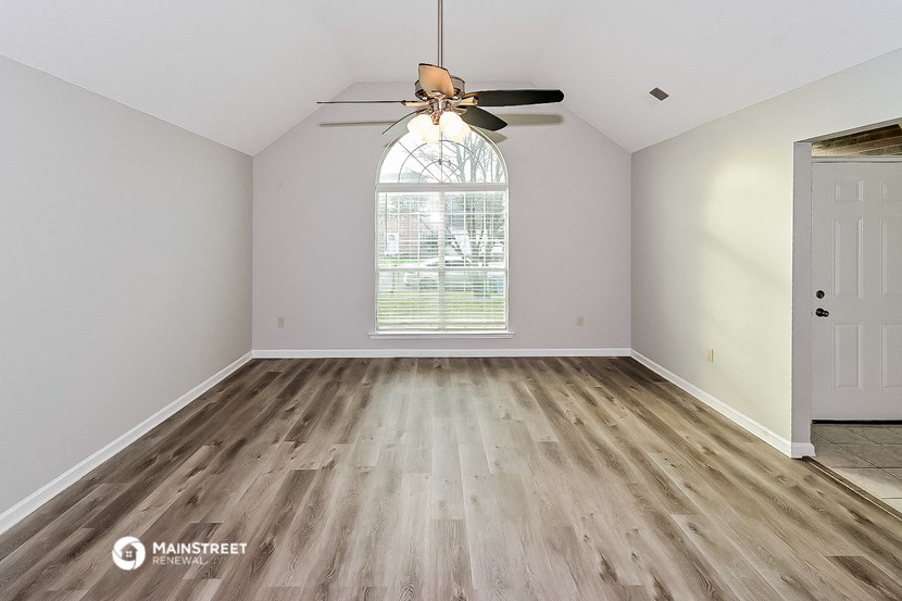 an empty living room with wood floors and a ceiling fan