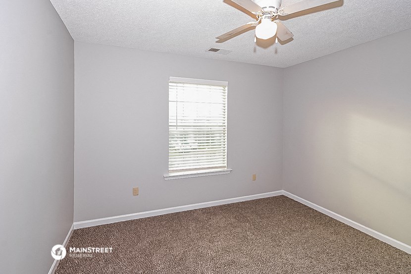 an empty bedroom with a ceiling fan and a window