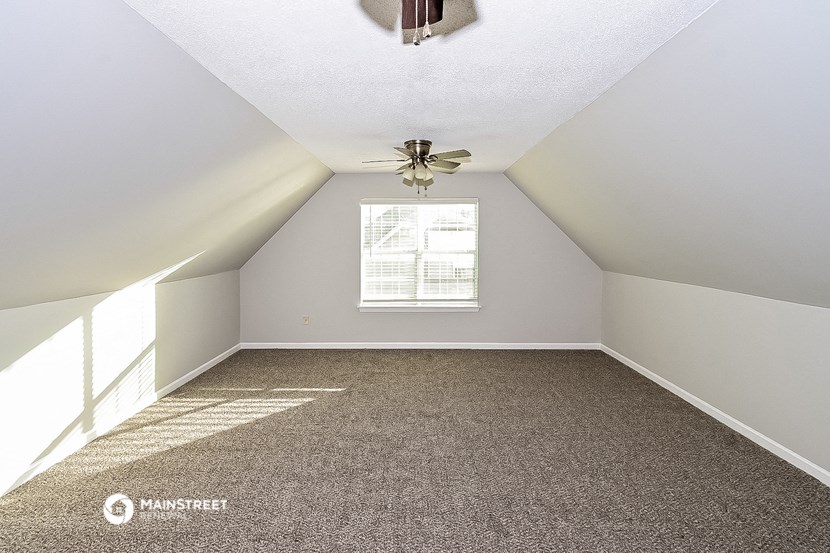 an attic room with carpet and a ceiling fan