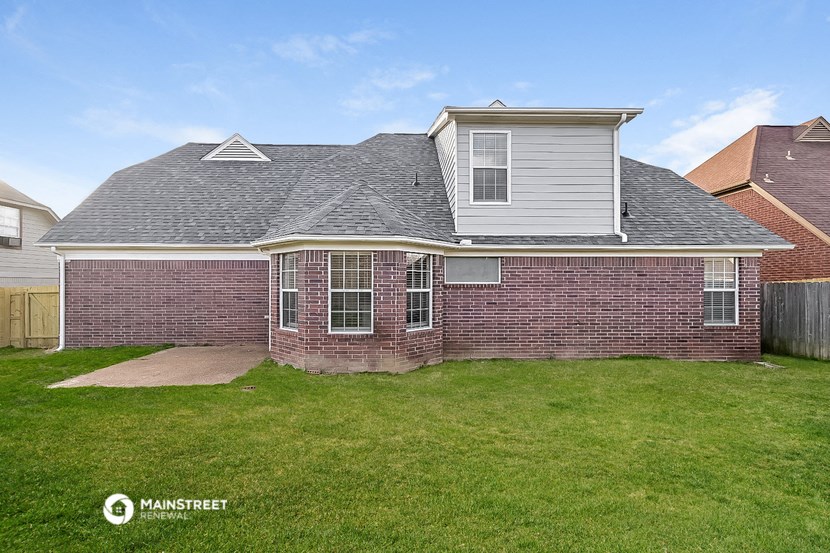a brick house with a grey roof and a yard