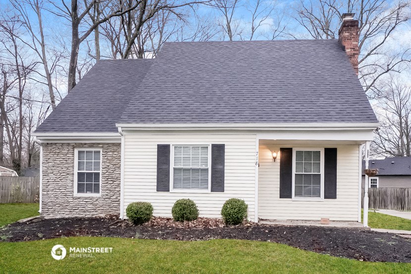 a small white house with black shutters and a yard