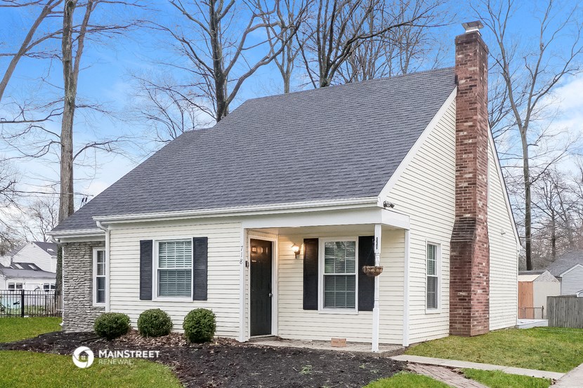a small white house with a black door and a brick chimney