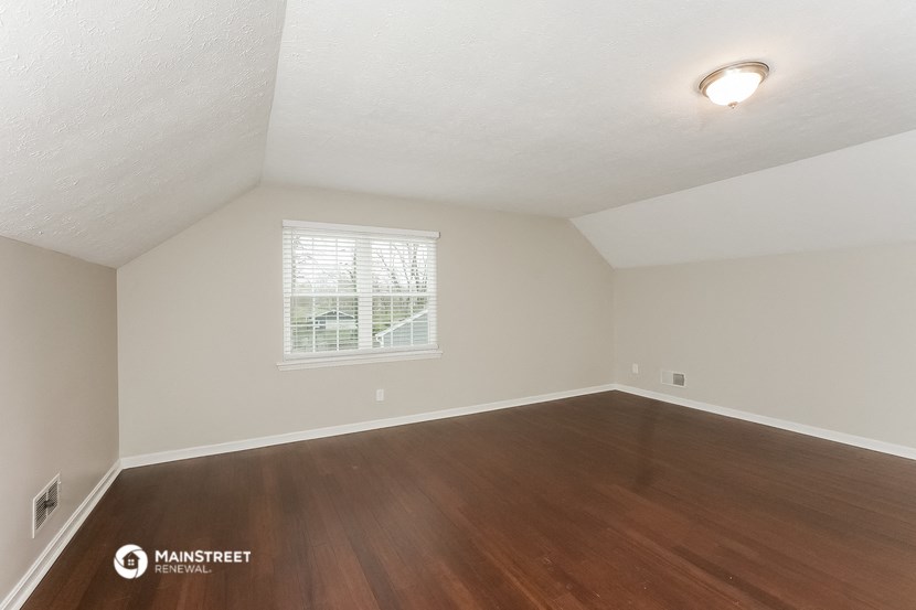 the spacious living room with hardwood flooring and a window