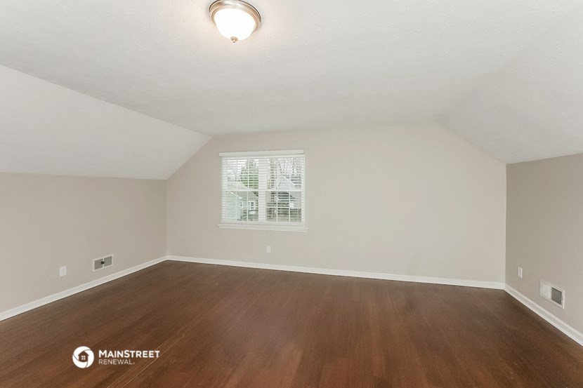 the spacious living room with hardwood flooring and a window