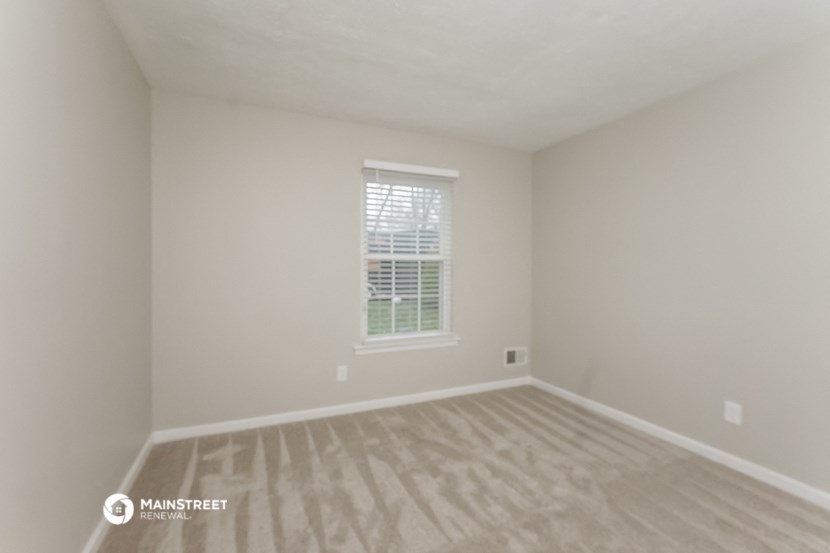 the upstairs bedroom with hardwood flooring and a window