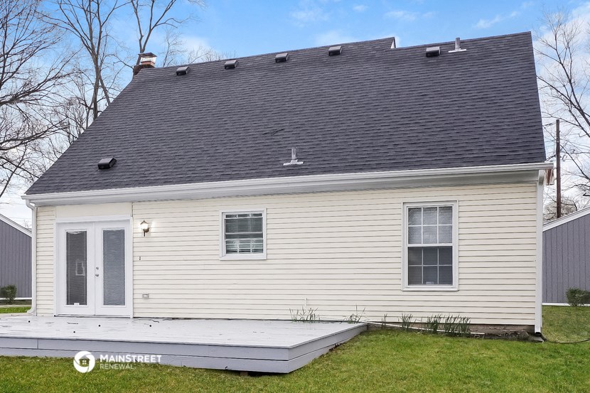 the back of a white house with a gray roof