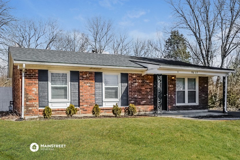 a brick house with black shutters and a lawn