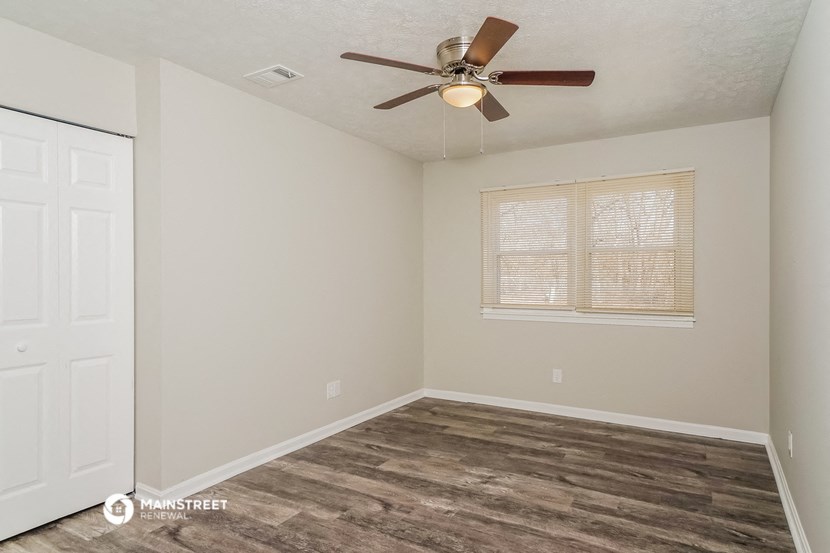 the spacious living room with a ceiling fan and a window
