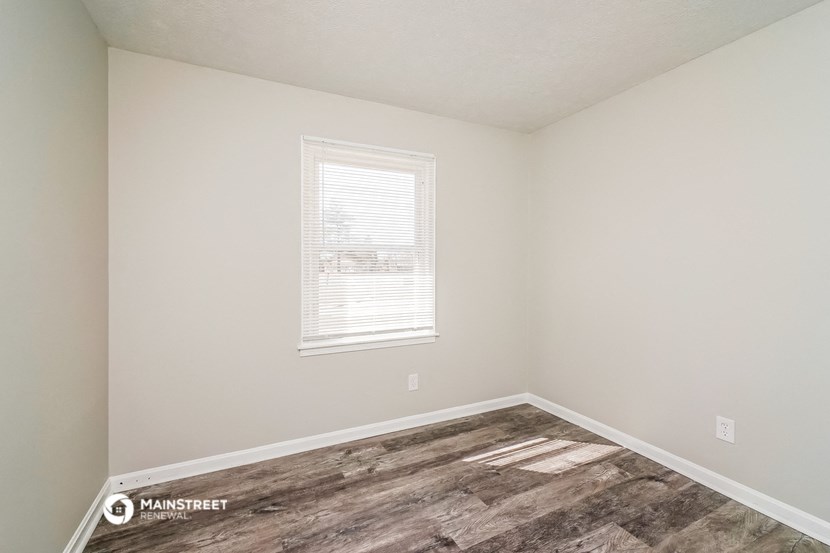 the interior of a bedroom with wood flooring and a window