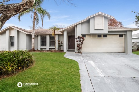 a white house with a driveway and a palm tree