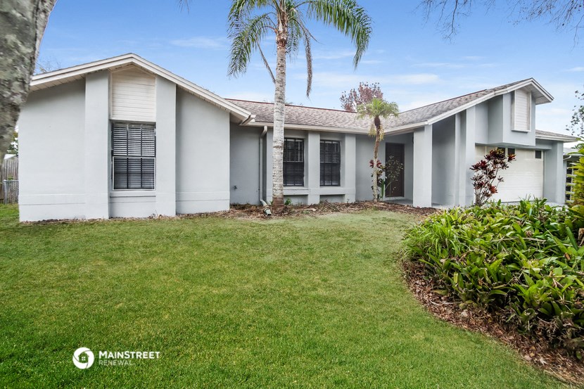 a white house with a lawn and palm trees