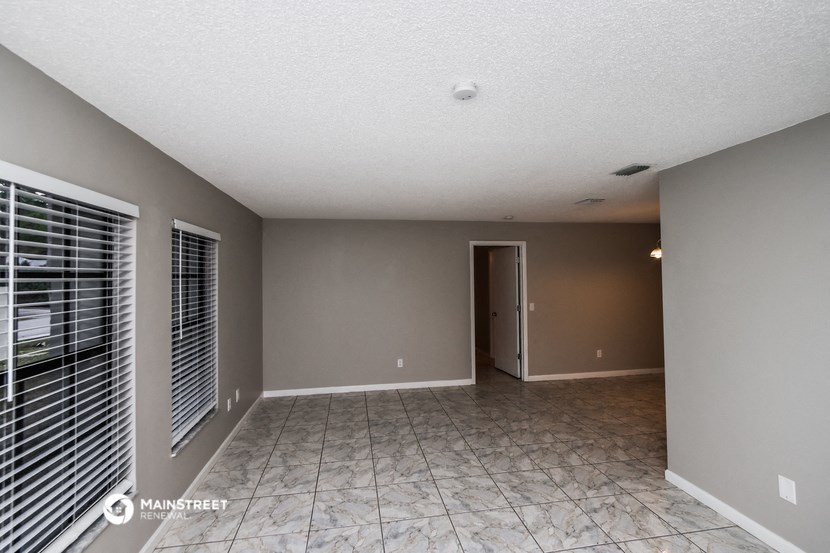 an empty living room with grey walls and a door to a hallway