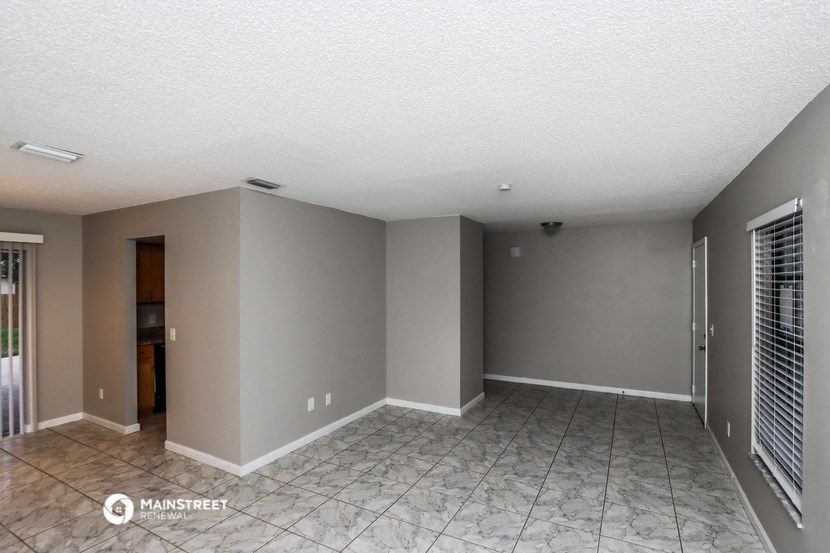 an empty living room with grey walls and a tile floor
