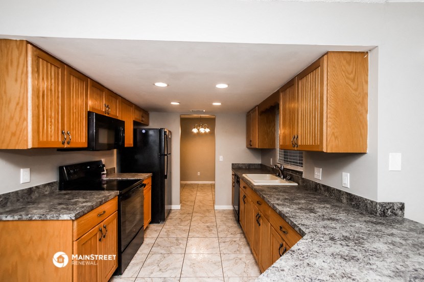 a kitchen with wooden cabinets and black appliances and marble counter tops
