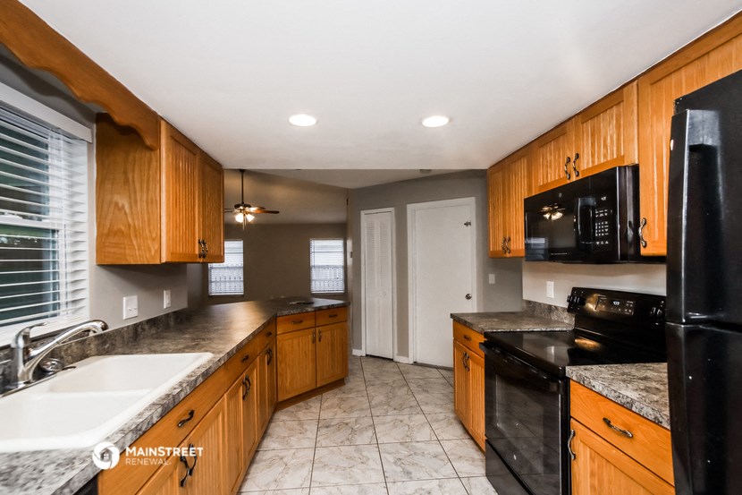 a kitchen with wood cabinets and black appliances and a sink