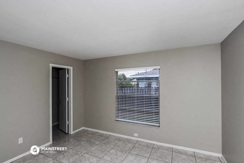 the spacious living room has a large window with blinds