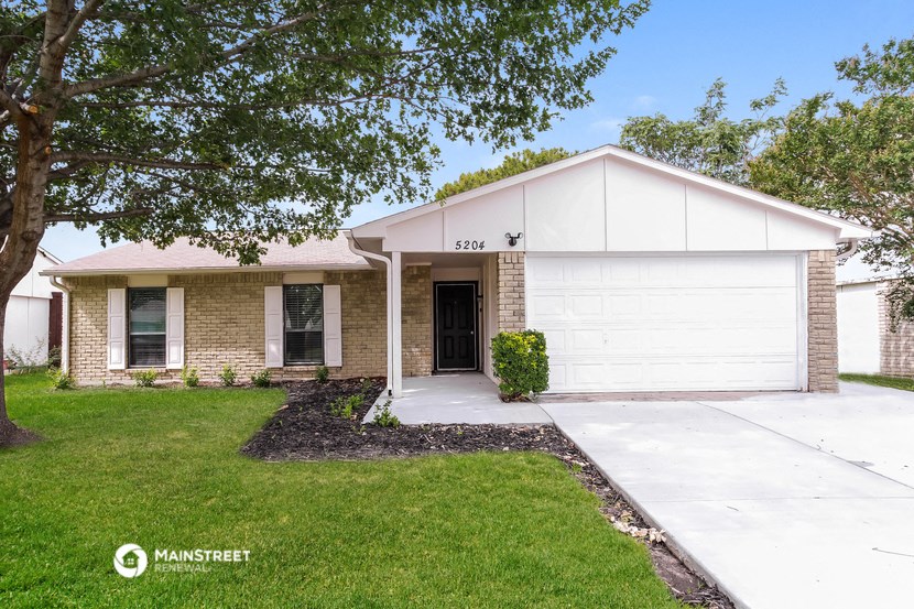 a white and brick house with a lawn and tree