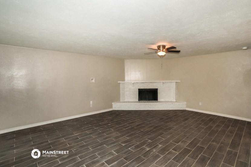the living room has a fireplace and a ceiling fan