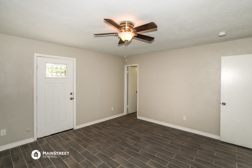 the empty living room of a house with a ceiling fan