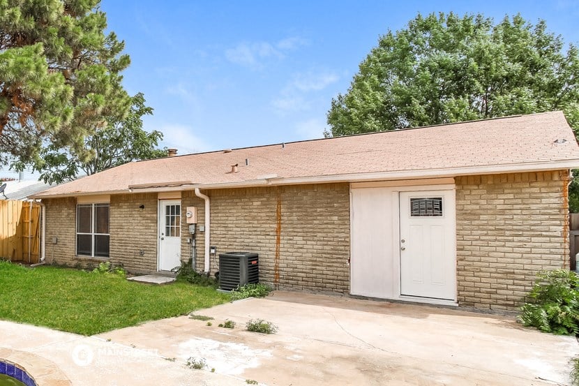 a small brick house with a white door and a driveway