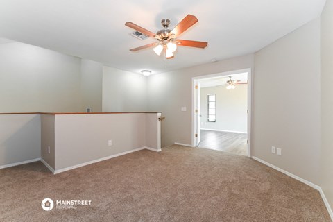 the living room and dining room with ceiling fan and carpet