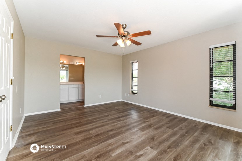 an empty living room with a ceiling fan and a bathroom
