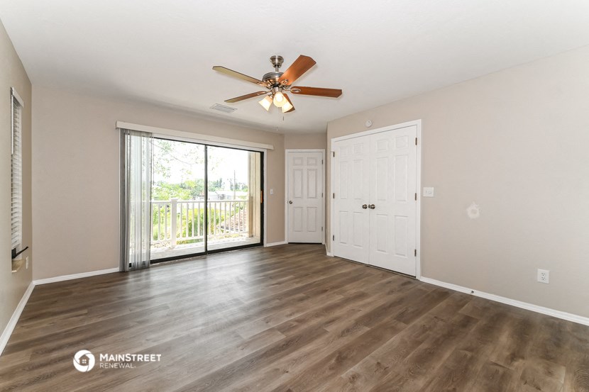 a living room with a ceiling fan and a door to a balcony
